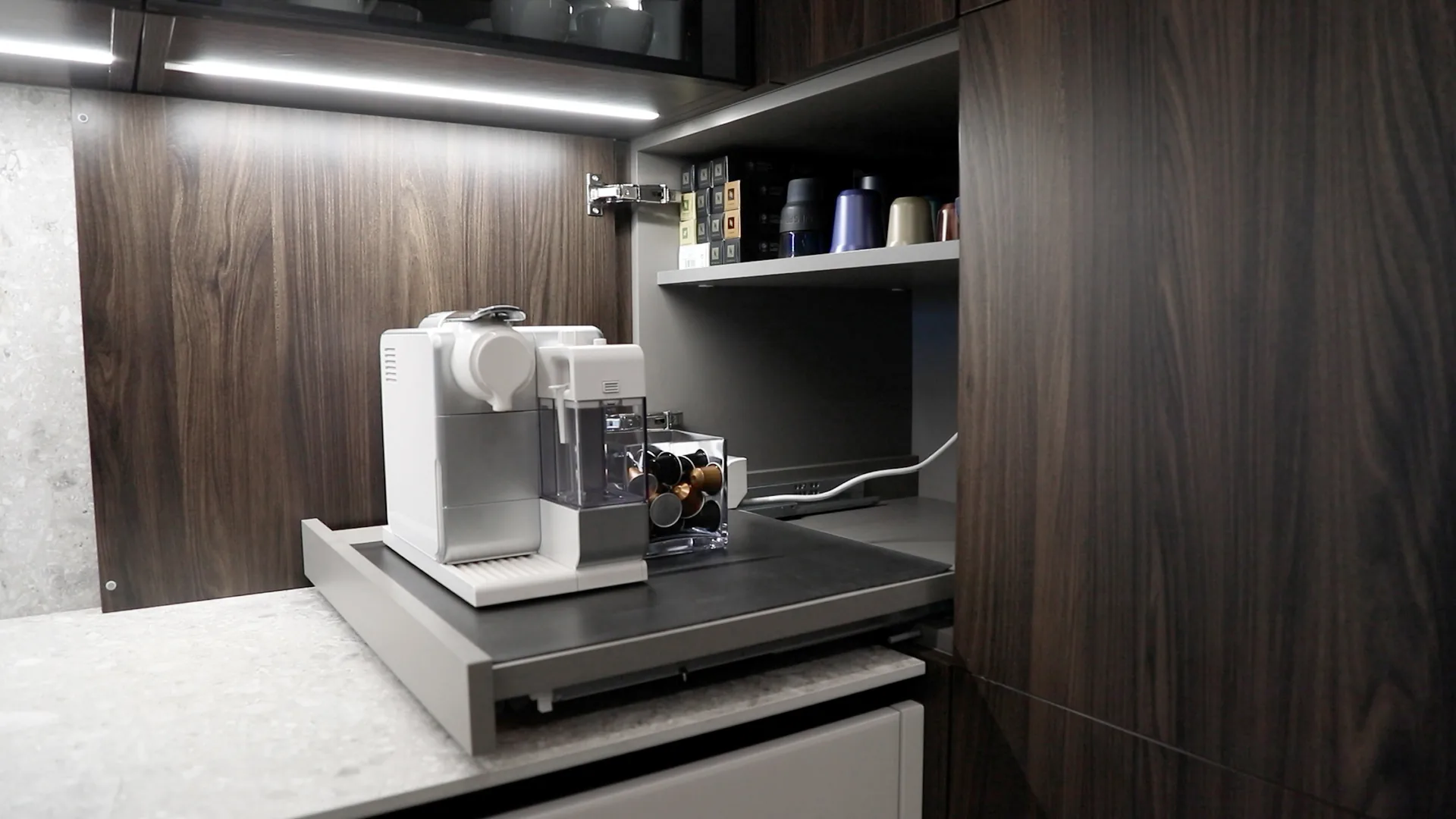 DV kitchen Dbayeh, Metn Lebanon — detail of integrated coffee station inside dark walnut tall unit with concealed pull-out shelf for Nespresso machine, recessed LED strip lighting and adjustable shelving for capsule storage — KITWOOD Lebanon completed project