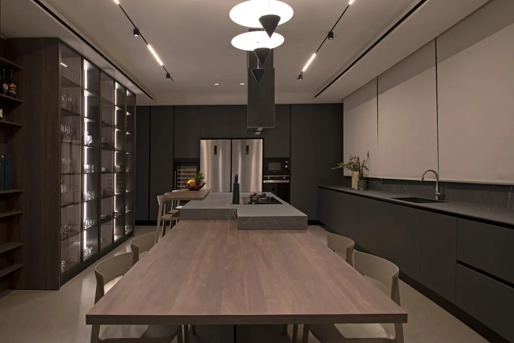 YK kitchen executed in Yarze, Baabda — long galley with Pietra Grey marble waterfall island, walnut dining table and illuminated walnut glass display wall — KITWOOD completed project